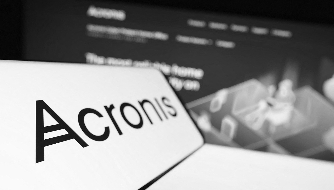 Mobile phone with logo of technology company Acronis International GmbH on screen in front of business website.