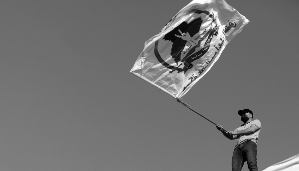 A supporter of Iran-backed Shiite militia Asaib Ahl al-Haq or 'League of the Righteous' waving its flag in Baghdad, Iraq, 14 July 2023.  