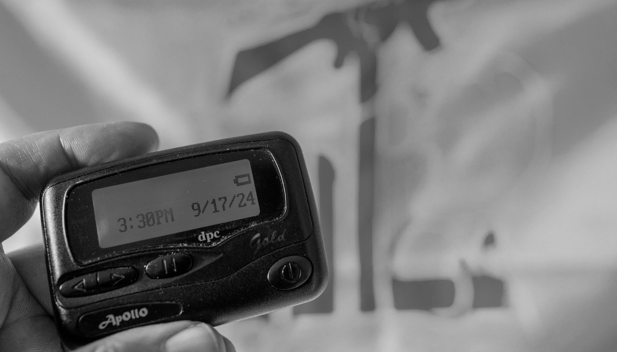 An Apollo beeper showing the date of Israel's deadly pager attack on Hezbollah, with the Lebanese Shiite group's flag in the background, on 17 September 2024.