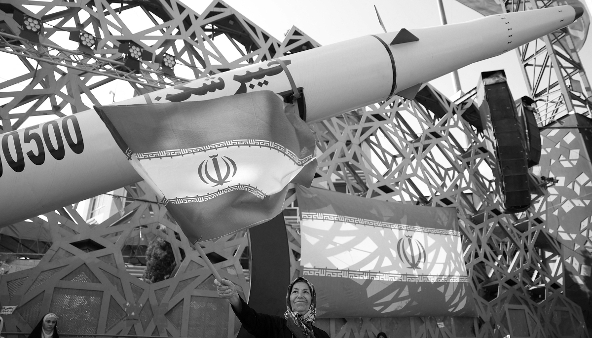 A woman waves the Iranian flag next to a model of the Iranian Kheibar Shekan ballistic missile in Tehran, on 4 June 2026.