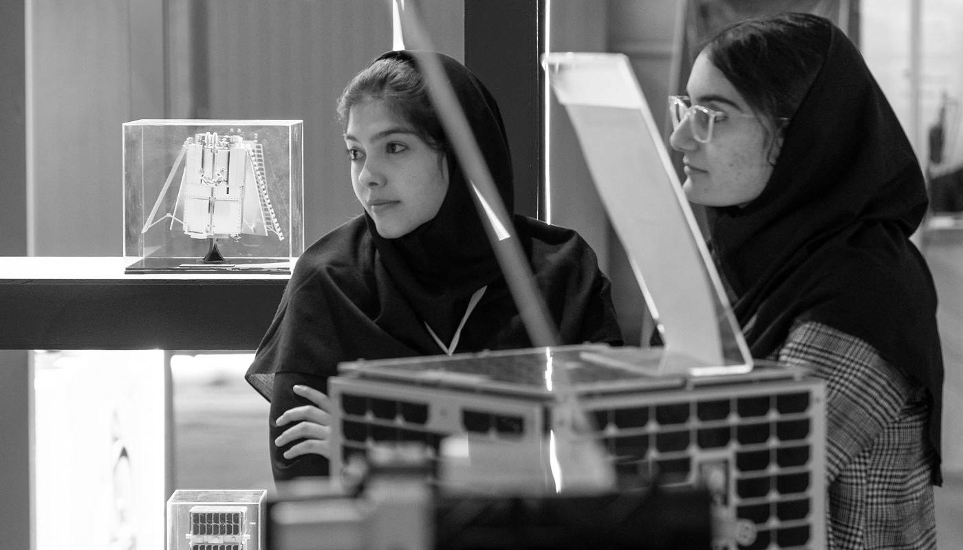 Two young female Iranian scientists stand together at the booth of the Iranian Space Research Center during an aerospace exhibition in Tehran, Iran, on 11 February 2025.