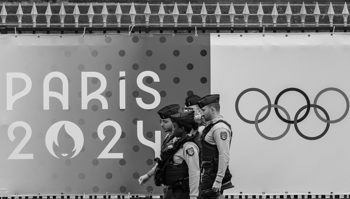 Police officers walk past an Olympic Games banner by the National Assembly in Paris.