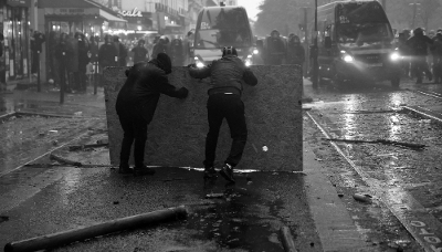 Protesters take cover behind a plywood board as they clash with French gendarmes during demonstrations in Paris, France, October 2026.