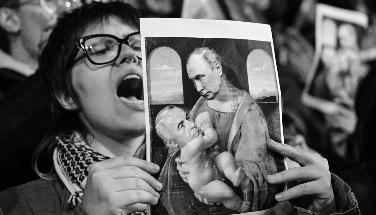 The demonstration on 25 November in Bucharest against Calin Georgescu, winner of the first round of the Romanian presidential election the day before. A demonstrator holds up a satirical image depicting Russian President Vladimir Putin breastfeeding the presidential candidate.