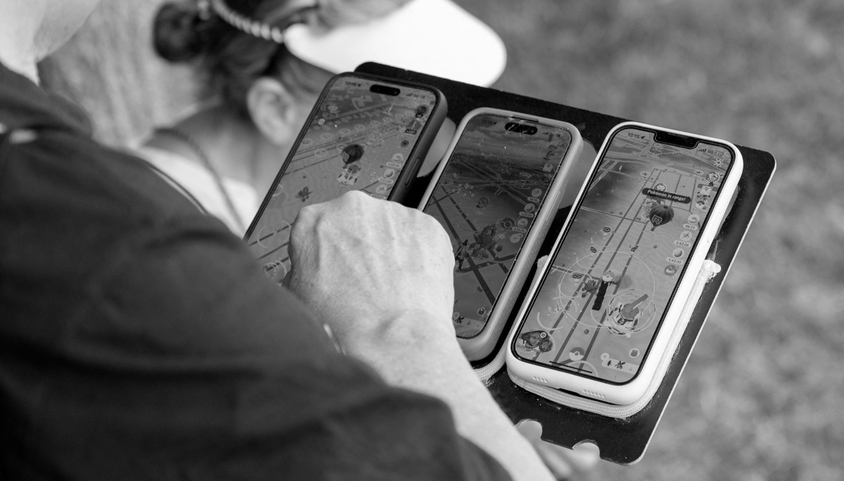 A fan plays Pokemon Go on three smartphones on the opening day of the Pokemon Go Fest 2025 near Paris, on 13 June 2025.

